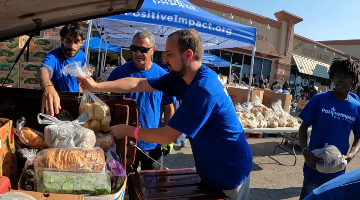 Volunteers passing bags of groceries at the Positive Impact distribution